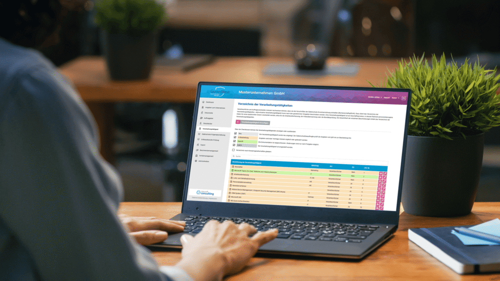 Eine Person arbeitet an einem Laptop, zeigt eine Softwareoberfl&auml;che mit Tabellen und Daten auf einem Holztisch.