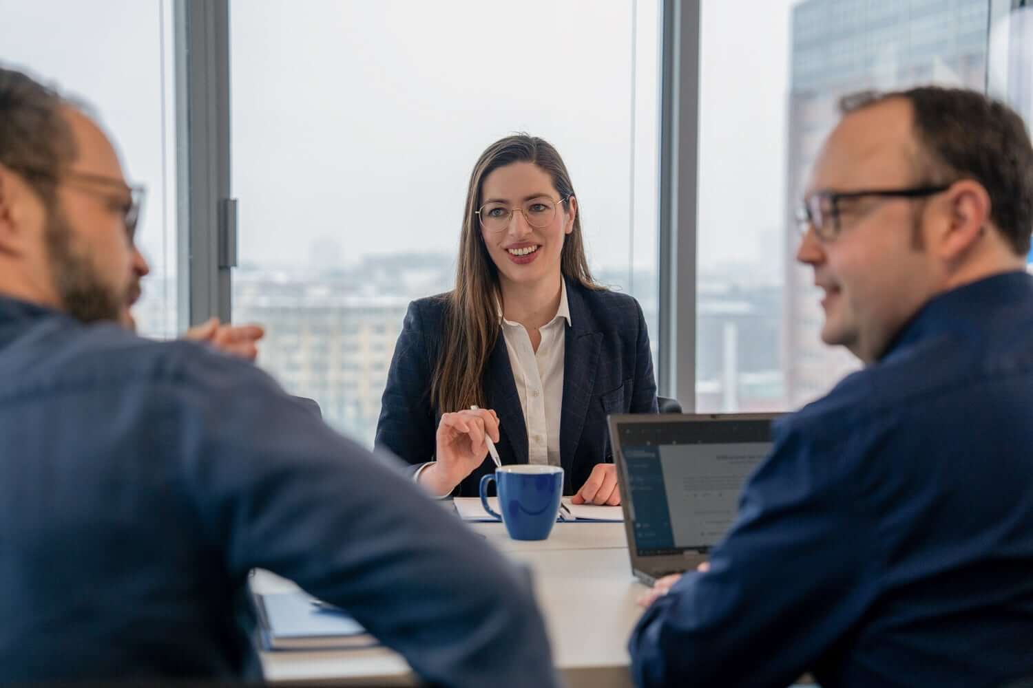 In einem Meeting in einem st&auml;dtischen B&uuml;rogeb&auml;ude beraten sich eine Datenschutzberaterin und zwei weitere Personen