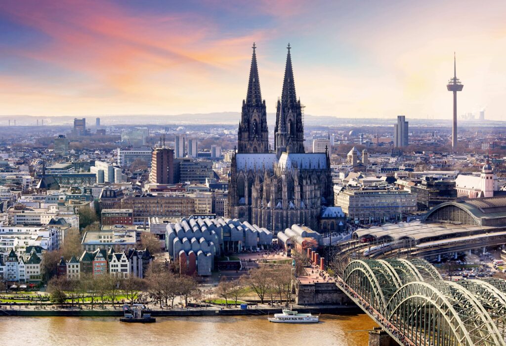 K&ouml;lner Dom mit seinen markanten T&uuml;rmen, umgeben von der Stadtlandschaft und dem Rhein, im Hintergrund der Fernsehturm.
