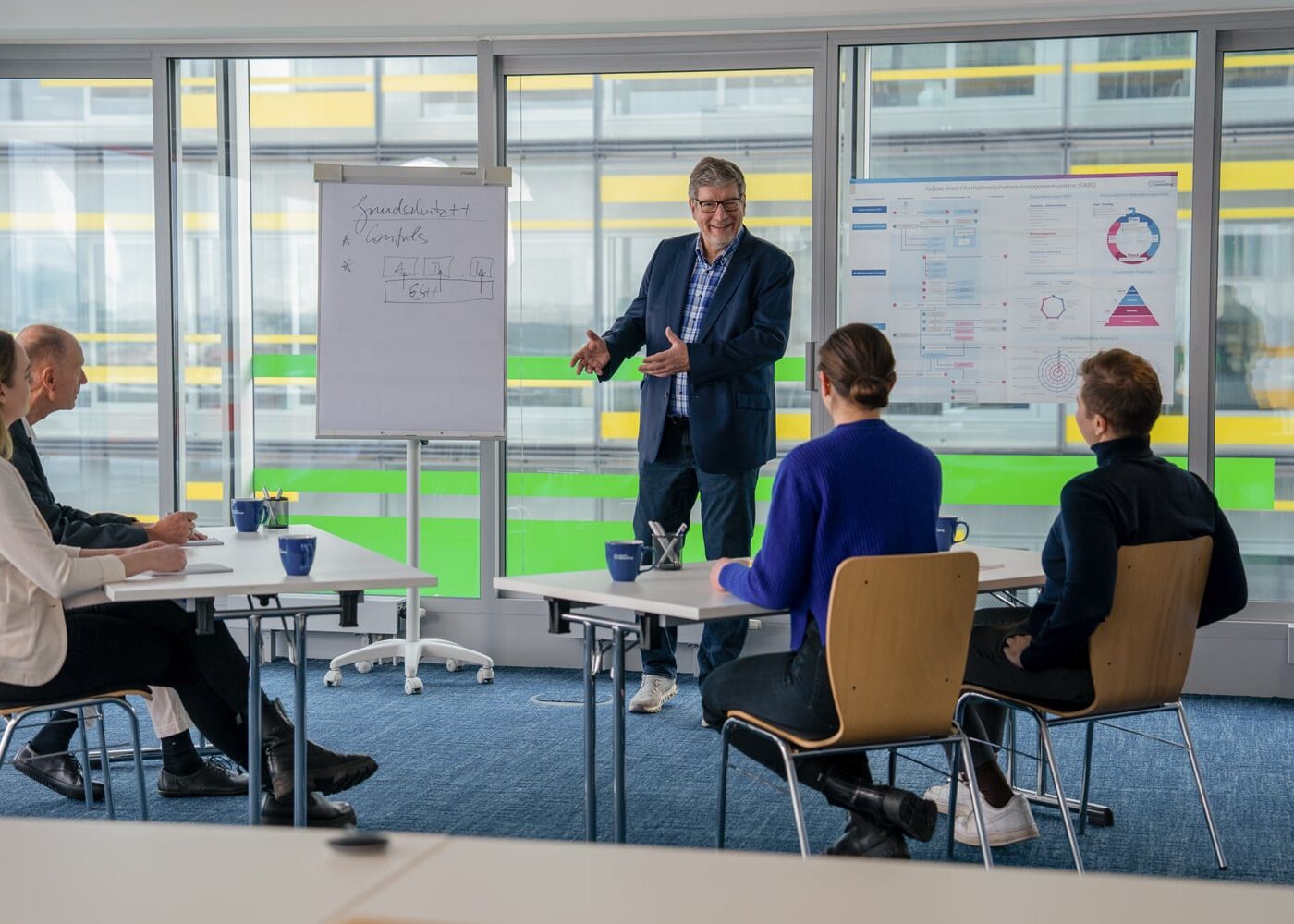 In einem Meeting teilt ein Consultant sein Wissen zur Informationssicherheit mit seinen Kolleginnen und Kollegen