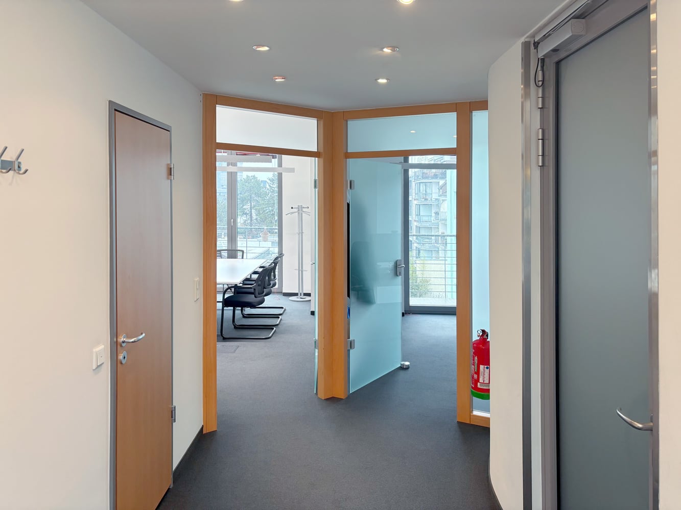 B&uuml;rogang mit Glast&uuml;ren, Besprechungsraum im Hintergrund und Feuerl&ouml;scher an der Wand.
