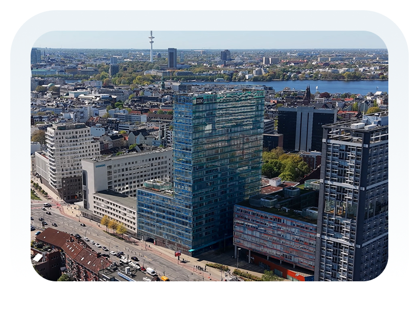 Moderne Architektur in einer Stadtansicht mit Wohn- und Bürogebäuden sowie der Alster im Hintergrund.